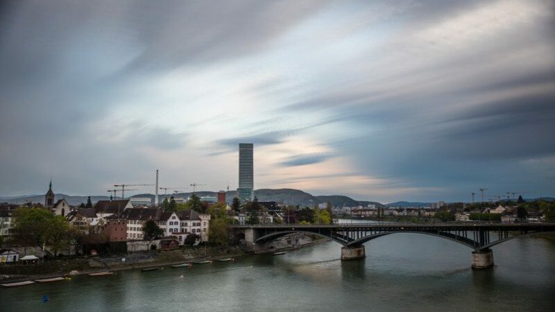 Imagem do rio a frente no final do dia do lado direito uma ponte e do lado esquerdo ao fundo várias casas e mais ao fundo o prédio da La Roche, o mais alto da cidade.