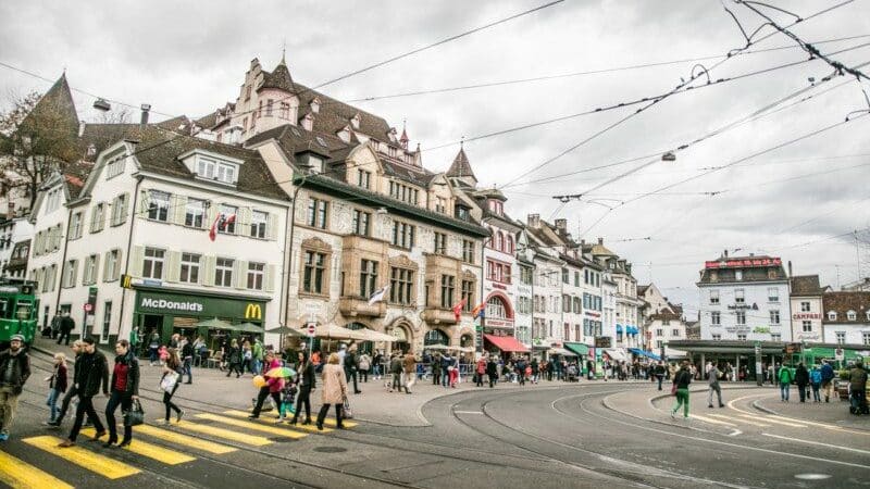 Imagem de duas ruas do lado direito e esquerdo da imagem em Barfüsserplatz durante o dia e ao fundo edifícios.