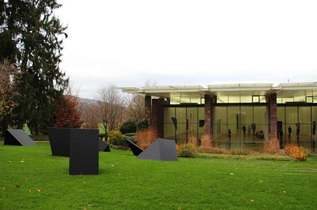 Imagem do Fondation Beyeler durante o dia com um jardim a frente com algumas esculturas e do lado direito ao fundo a galeria. Representa o que fazer em Basel.