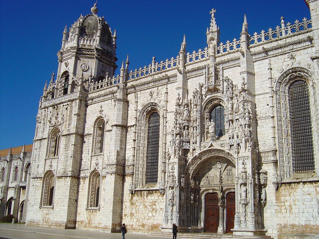 Imagem do Mosteiro dos Jerónimos durante o dia com a igreja do lado direito da imagem. Representa o que fazer em Lisboa.