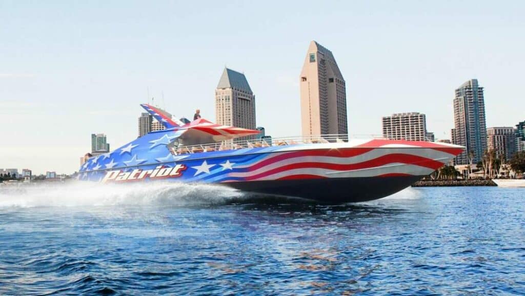 Jet Boat pintado com a bandeira dos Estados Unidos andando pela Baía de San Diego. Ele espirra água por onde passa.