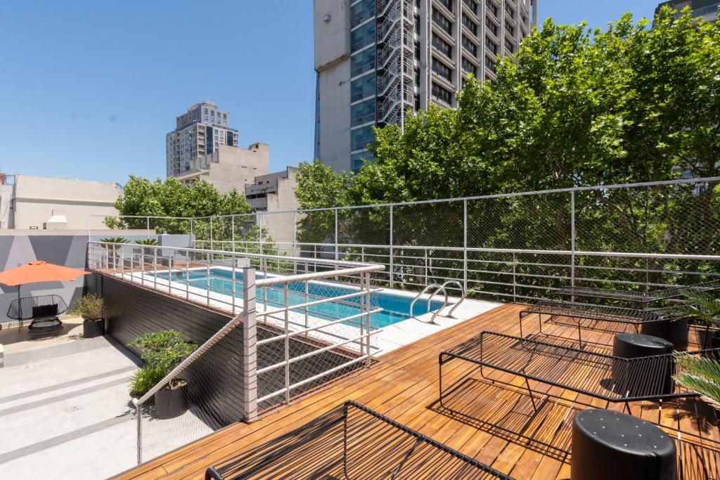 piscina retangular no terraço e com espreguiçadeiras em um deck de madeira em estilo moderno e com vista para a cidade no Hotel Bys Palermo, um dos hotéis 4 estrelas para família em Buenos Aires