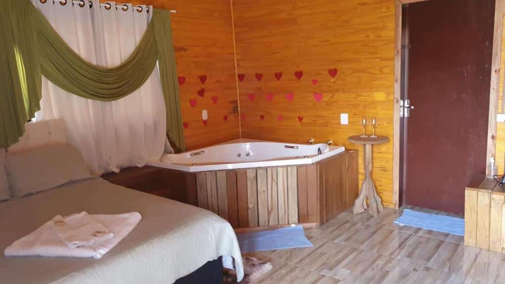 Quarto do Pousada Rio Canoas, com cama e banheira de hidromassagem de canto.
