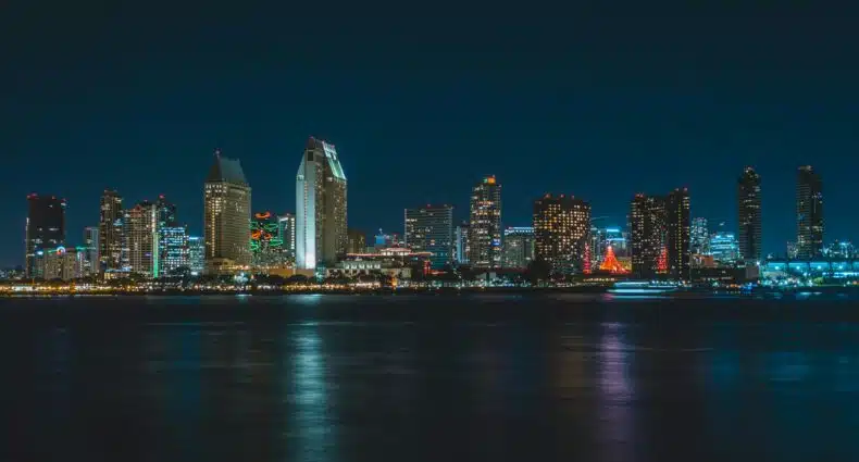 Foto da Baía de San Diego durante a noite. Os prédios e construções ficam iluminados e refletem na água. A foto ilustra o post de o que fazer em San Diego.