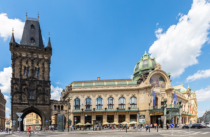 Imagem durante do dia da Torre da Pólvora do lado esquerdo da imagem e do lado direito a Casa Municipal de Praga com a rua a frente cheia de pessoas andando. Representa o que fazer em Praga.