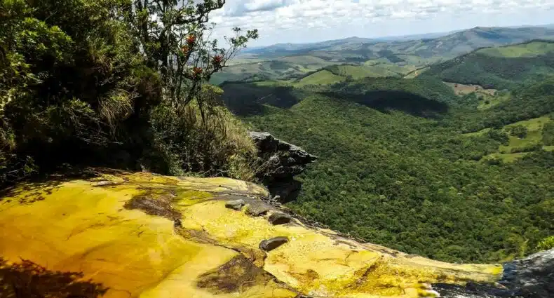 Atração do Parque Estadual do Ibitipoca que chama Janela do céu com uma borda infinita. A vista da cachoeira dá para as montanhas e para o céu limpo durante o dia. Imagem ilustrando post O que fazer em Ibitipoca.