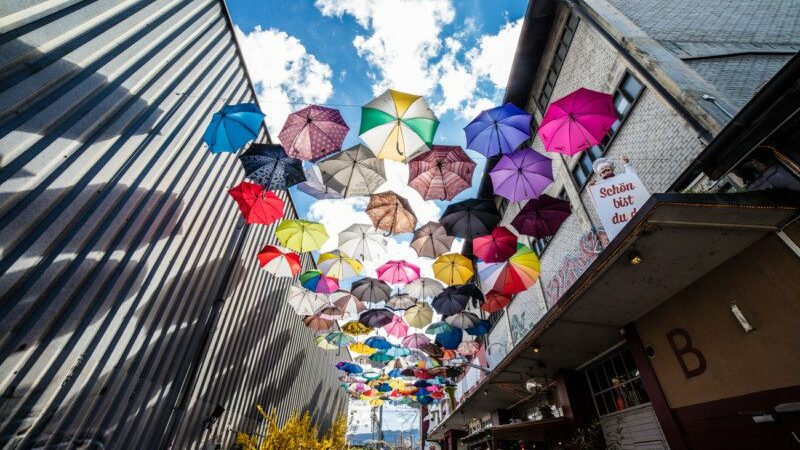 Imagem do Zürich West, Kreis 5 Quarter durante o dia no centro da imagem guarda-chuvas coloridos e do lado direito edifícios. Representa o que fazer em Zurique.