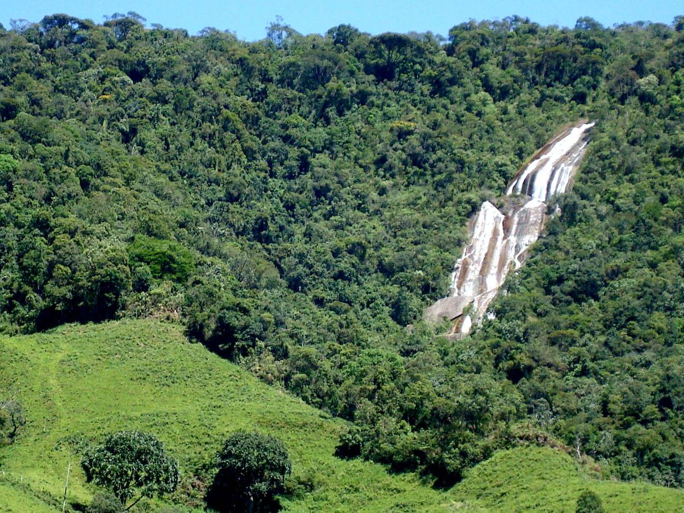 Imagem aérea da Cachoeira do Alcantilado que faz parte do Sítio Cachoeiras do Alcantilado em Visconde de Mauá. A cachoeira fica no meio de uma mata fechada e sua queda d'água pode ser vista de longe.