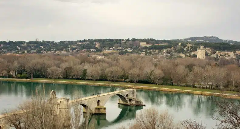 Imagem de Avignon durante o dia com ponte do lado esquerdo no centro da imagem em baixo um rio e do outro lado árvores e a cidade. Representa o que fazer em Avignon.