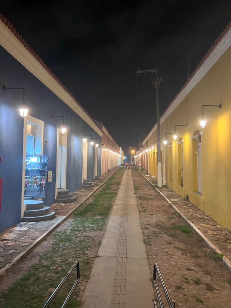 Imagem do Centro Histórico de Parnaíba no anoitecer com uma ruela no centro da imagem e em cada lado la imagem lojinhas.