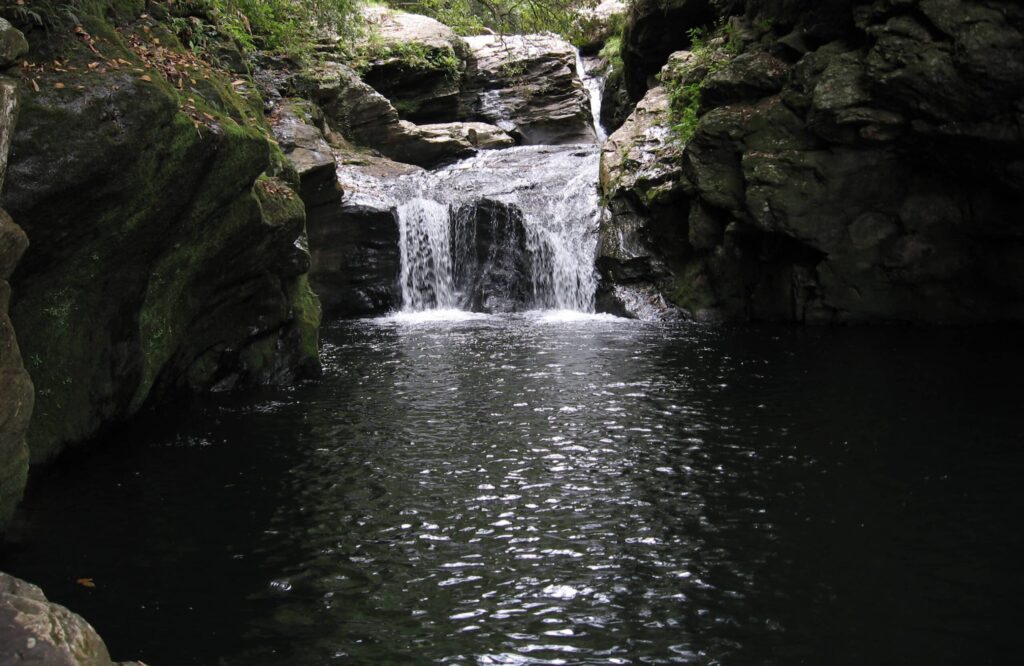 Cachoeira do Tenebroso em Delfinopólis, uma queda d'água baixa, cercada por rochas, onde forma-se um lago