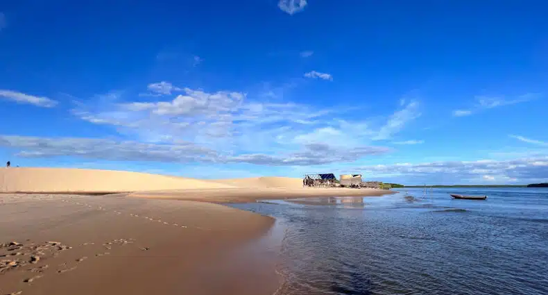 Imagem do Delta do Parnaíba durante o dia com rio do lado direito e do lado esquerdo dunas de areia. Representa o que fazer no Delta da Parnaíba.