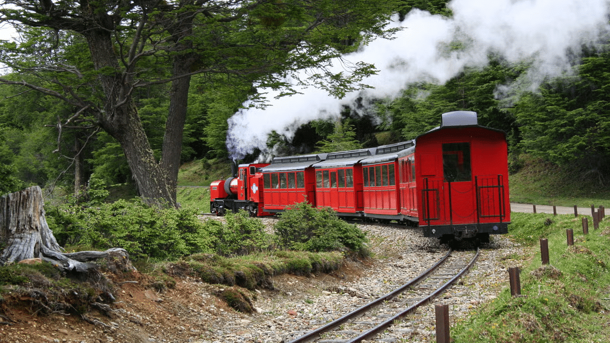 Imagem de um trem fazendo a curva, ao redor área verde. Imagem para ilustrar post sobre passeios em Ushuaia.