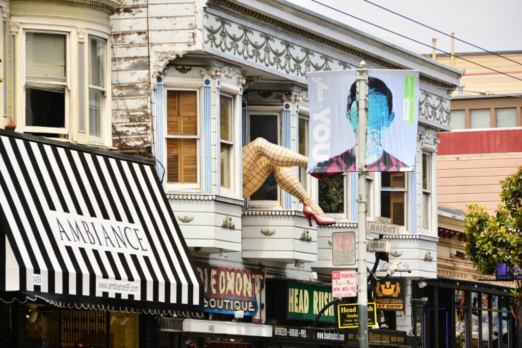 Prédio no bairro Painted Ladies. Na janela há uma grande escultura de pernas com meia-calça e salto vermelho.