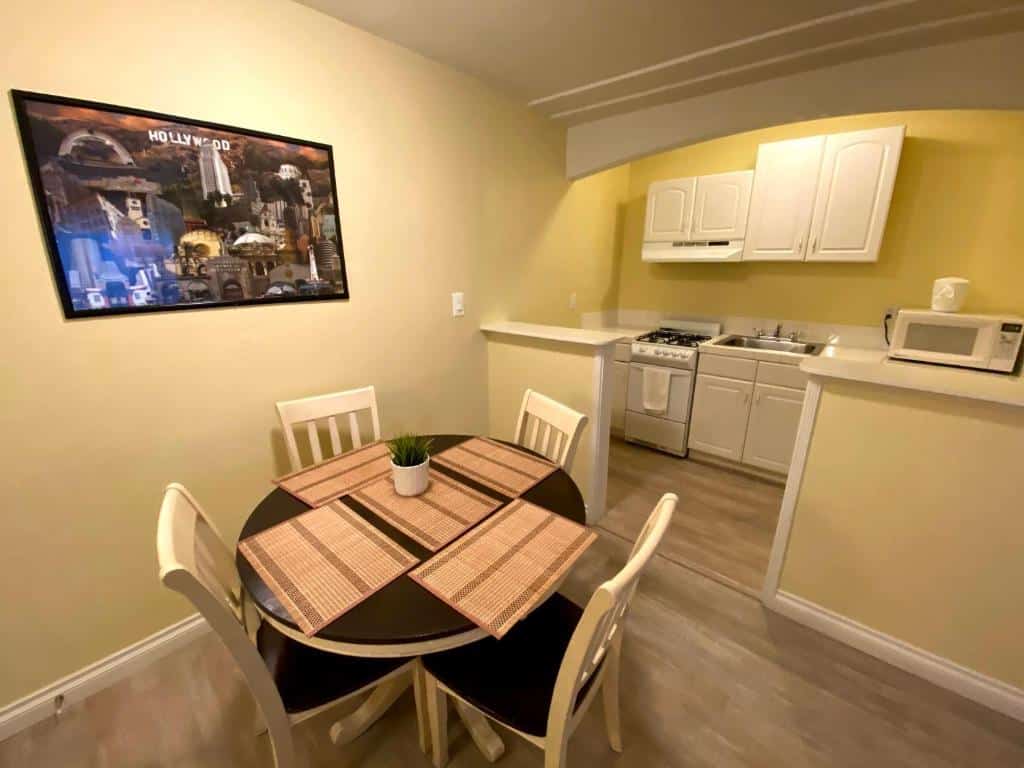 Uma mesa de jantar do lado esquerdo no Hollywood Celebrity Hotel. Do lado direito um cozinha bem equipada.