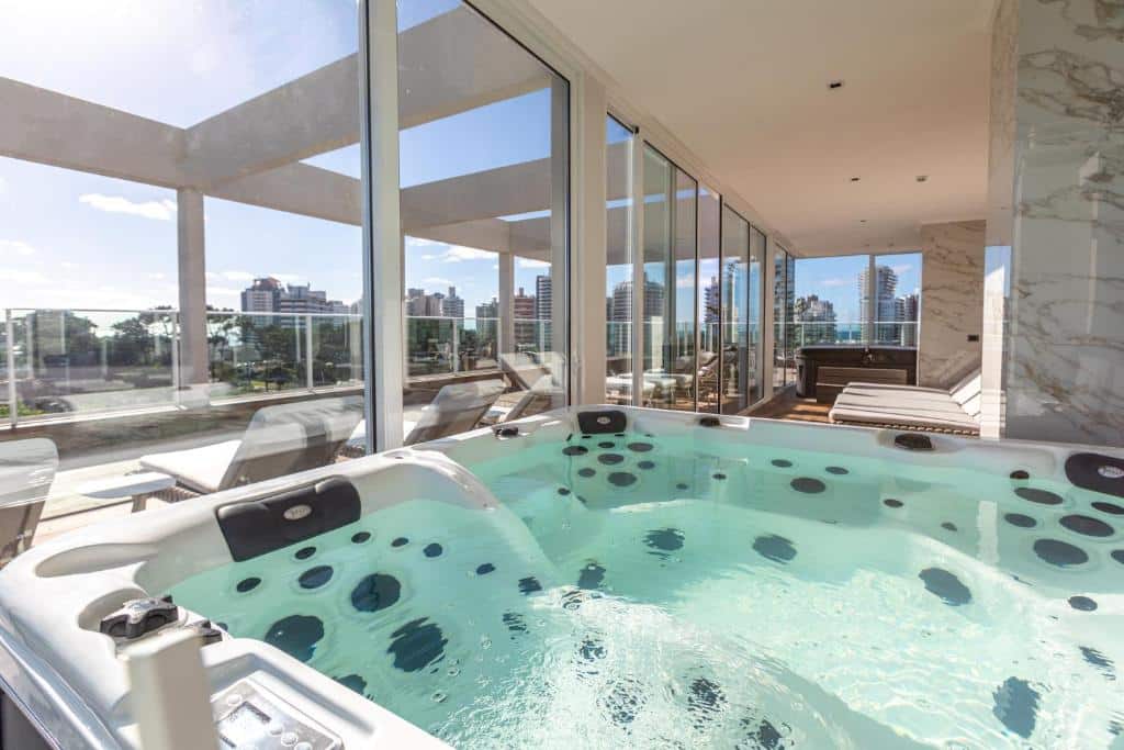 Jacuzzi no Hotel Solerios com água borbulhante, situada em um ambiente com grandes janelas de vidro que oferecem uma vista panorâmica da linha do horizonte de uma cidade.