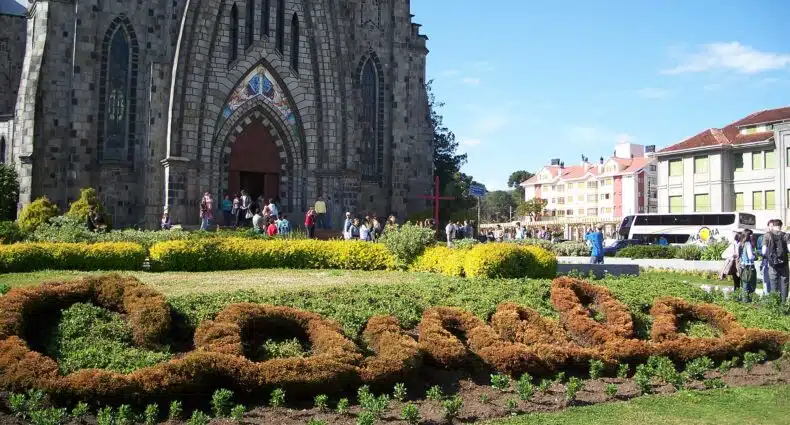 gramado em frente à imponente Igreja de Pedra com as plantas baixas formando a palavra Canela