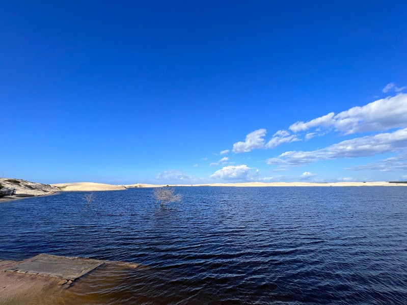 Imagem da Lagoa do Portinho durante o dia com lago a frente e ao fundo dunas. Representa o que fazer no Delta do Parnaíba.