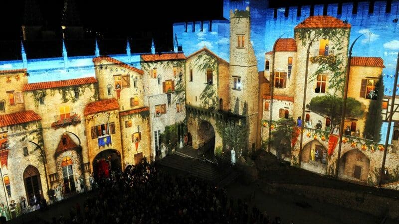 Imagem do Festival d'Avignon com a imagem de castelos projetados na parede. Representa o que fazer em Avignon.