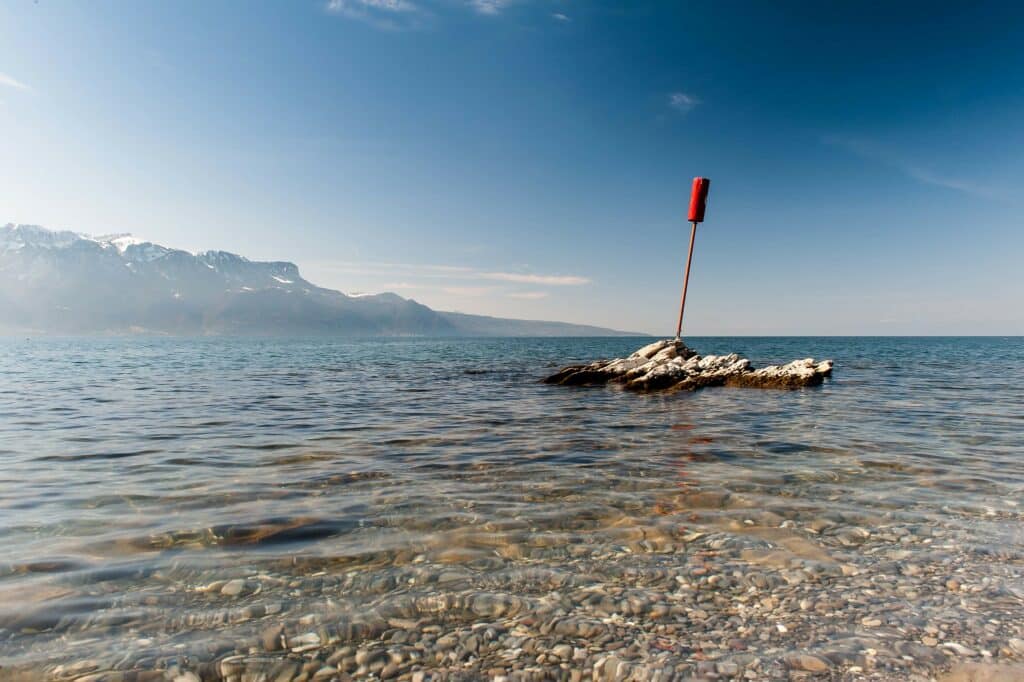 Imagem do La Plage de la Grotte durante o dia com o mar a frente e ao fundo do lado esquerdo montanhas.