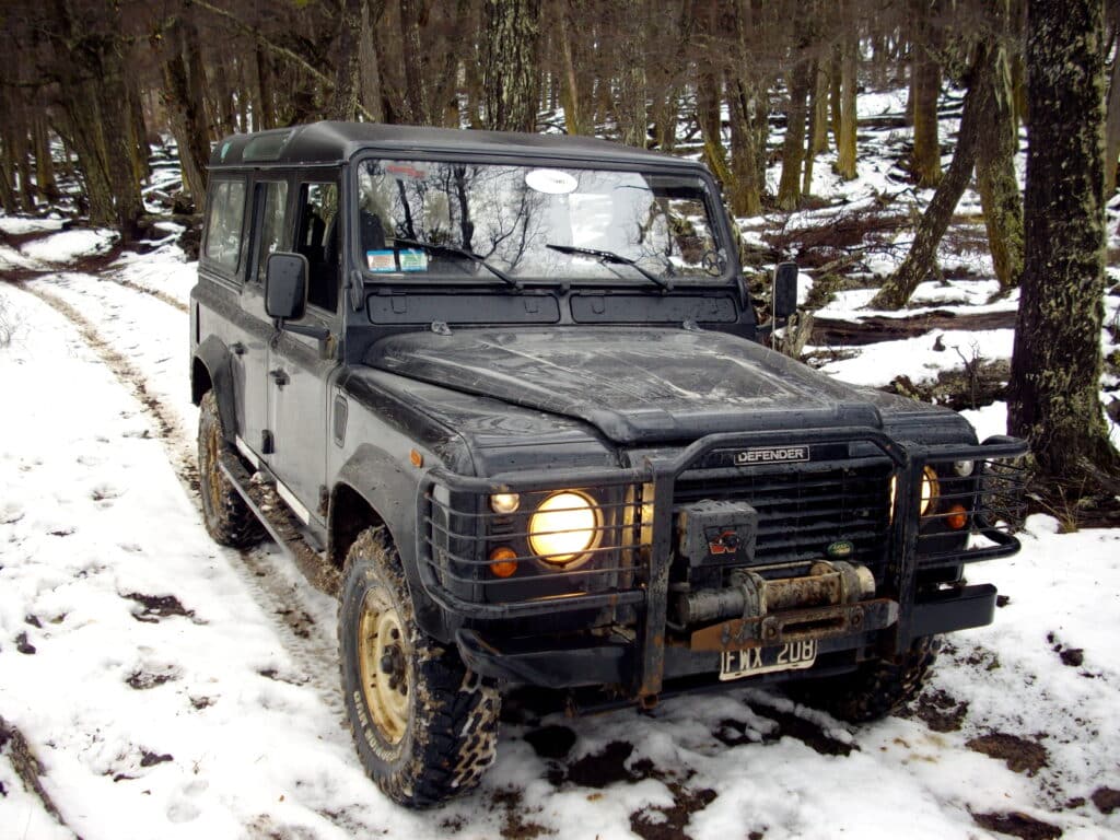 Carro 4x4 na neve em Ushuaia. No fundo árvores. Imagem para ilustrar post sobre como chegar em Ushuaia.