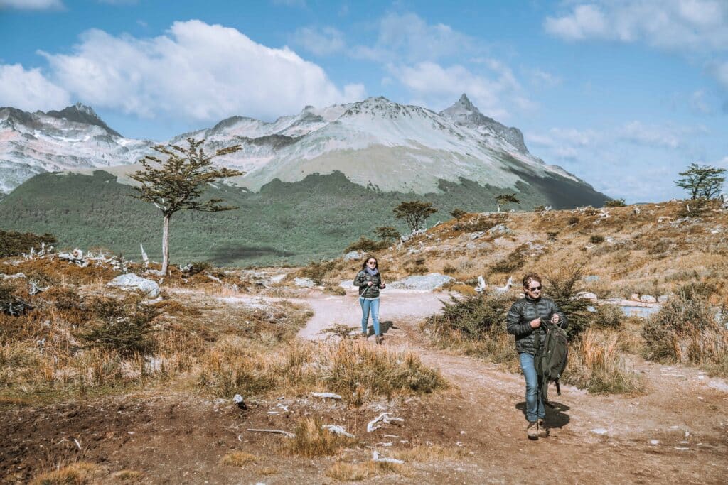 Duas pessoas fazendo a trilha na Laguna Esmeralda, no fundo montanhas. Imagem para ilustrar post sobre transportes em Ushuaia.