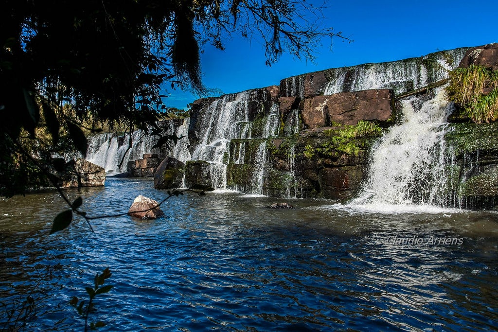 Vista da Cachoeira dos Venâncios. Do lado esquerdo árvores e pedras. Imagem para ilustrar post sobre o que fazer em Cambará do Sul.