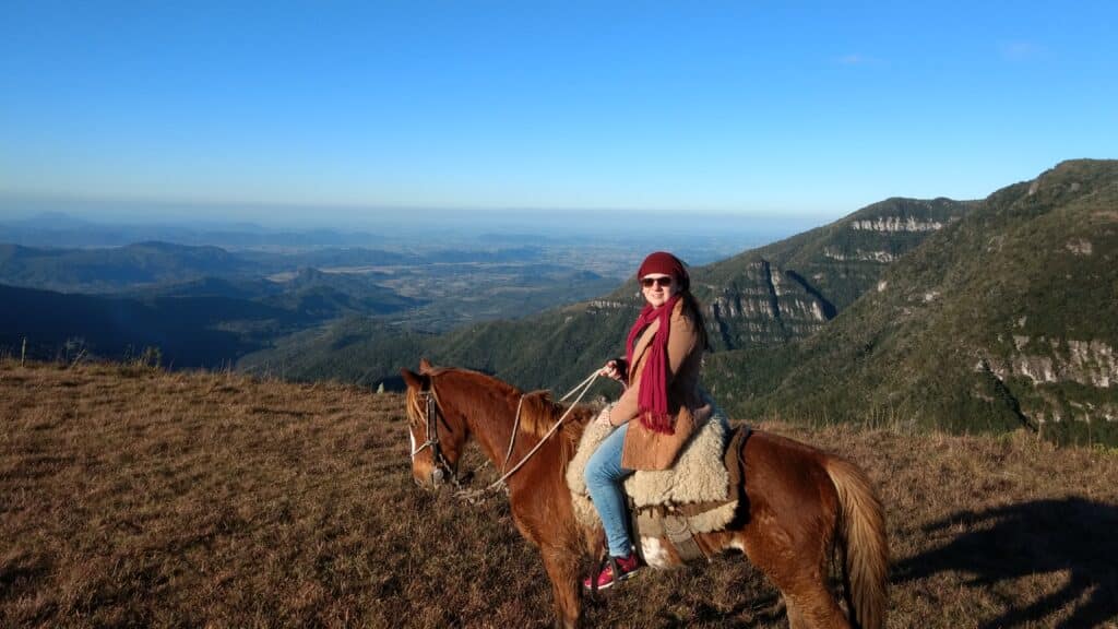 Uma pessoa fazendo cavalgada, no fundo a vista das montanhas.