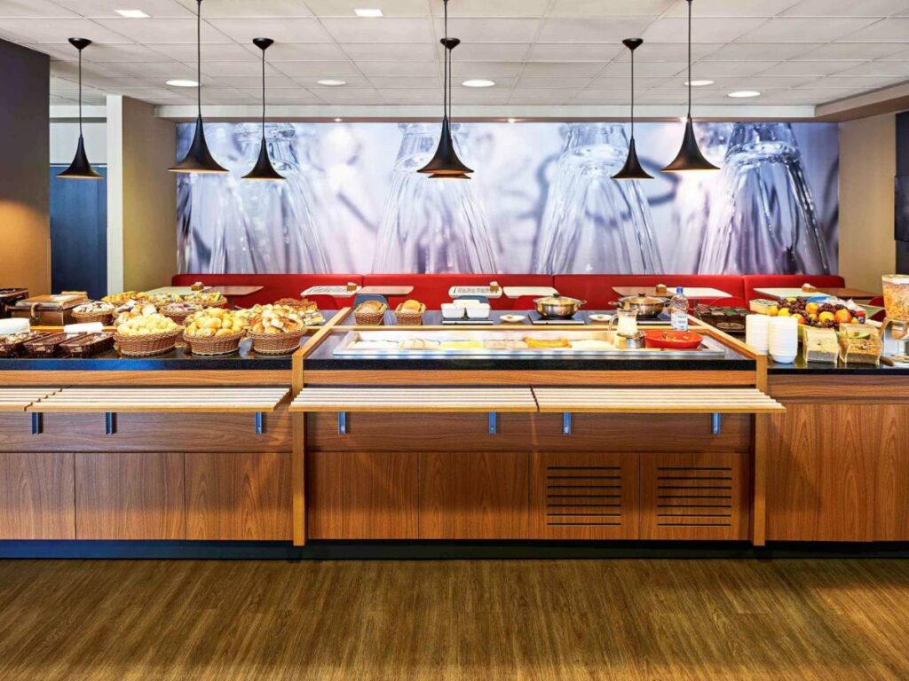 Área de refeições do Ibis Florianopolis. Um balcão com café da manhã.