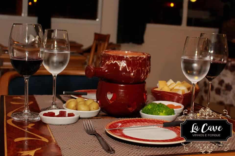 Uma imagem do fondue com taças ao redor e aperitivos.
