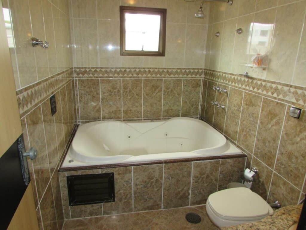 Banheiro do Pleasant Place Hotel. Uma banheira no fundo, do lado direito um vaso sanitário.