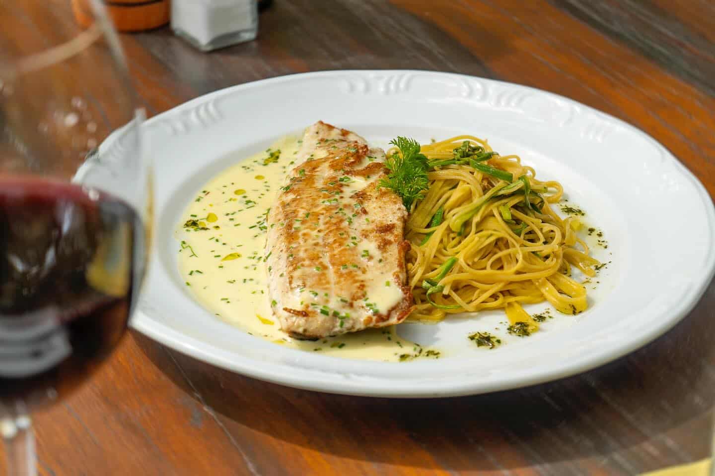 Prato do restaurante Rosmarinus Officinalis em Visconde Mauá e do lado uma taça de vinho.