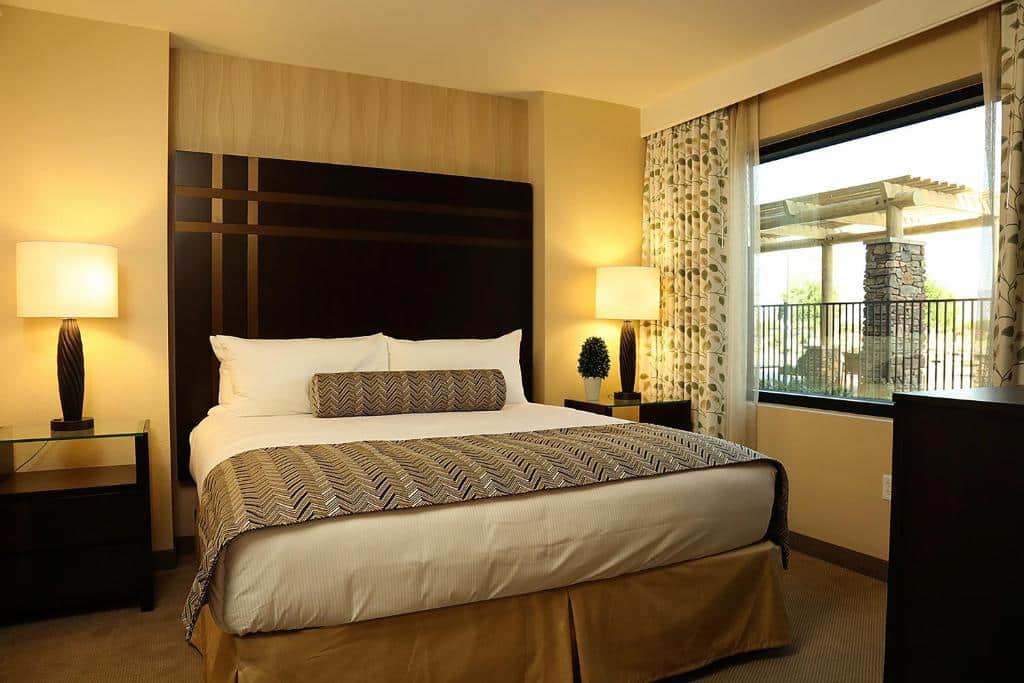 Quarto do The Berkley com uma cama de casal ao lado de uma janela, no lado direito. Dos seus dois lados estão mesinhas com abajur.