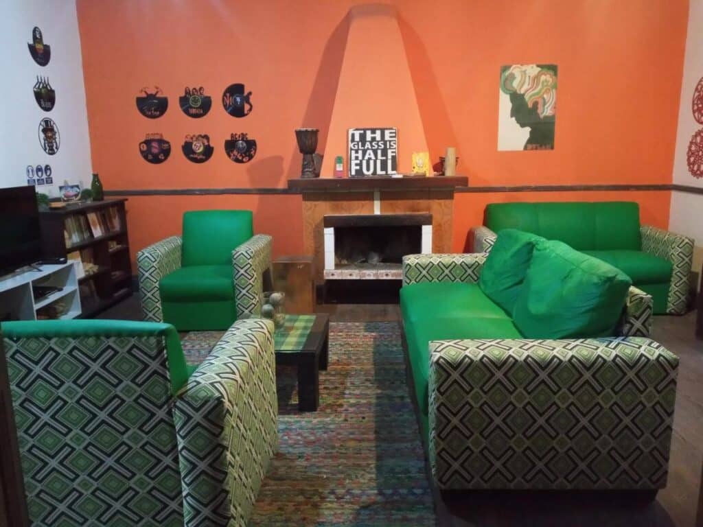 Lounge compartilhado da Casa Copada, com sofás, poltronas, TV e uma lareira. Imagem para ilustrar post sobre hostels em Montevidéu.