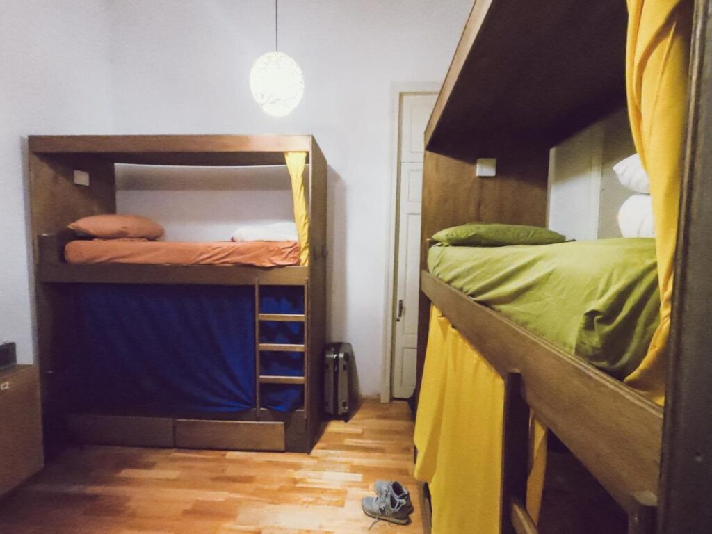 Quarto do Charruas, do lado direito e do lado esquerdo uma cama de beliche, no fundo a porta do quarto.