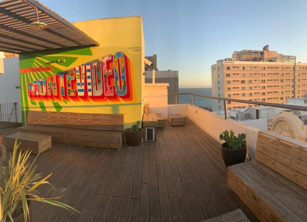 Terraço do Circus Hostel&Hotel Montevideo, com banos de madeira e vista do mar e prédios. Imagem para ilustrar post sobre hostels em Montevidéu.