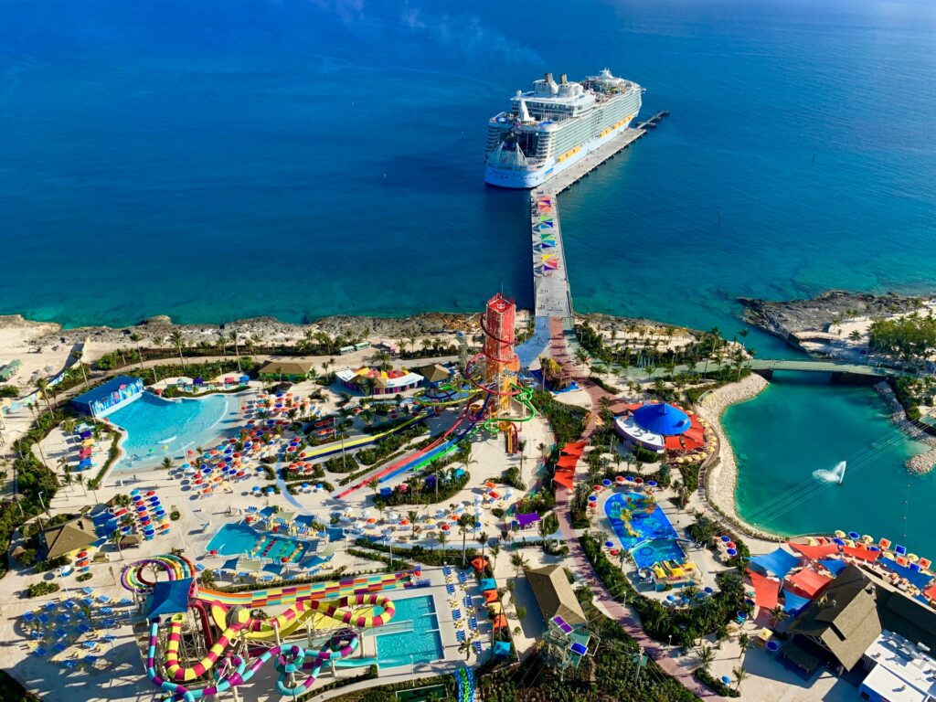 Imagem área de um parque aquático localizado em CocoCay nas Bahamas. O parque aquático tem vários brinquedos e atrações, como piscinas, tobogãs e em volta dele está o mar azul e um grande navio parado perto de um cais. Imagem ilustrando post Hotéis nas Bahamas.
