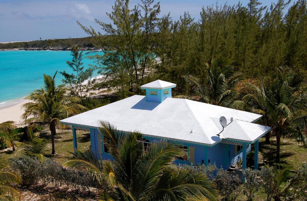 Imagem aérea da casa do Paradise Bay Bahamas que mostra uma propriedade térrea na cor azul com várias árvores em volta e em frente do lado esquerdo o mar azul durante o dia. Imagem ilustrando post Hotéis nas Bahamas.