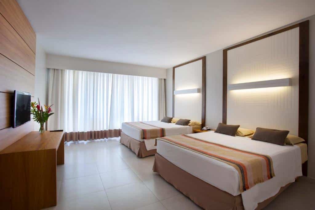 Quarto espaçoso e moderno, com duas camas de casal e decoração minimalista em tons neutros. Um dos hotéis no Rio Quente Resorts.