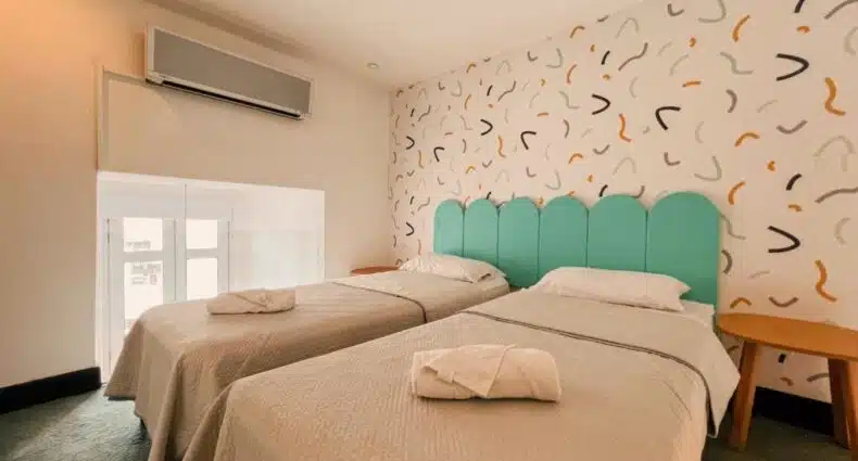 Quarto do Viajero Montevideo para ilustrar post sobre hostels em Montevidéu. Duas camas de solteiro com uma cabeceira, no fundo uma janela e um ar-condicionado.