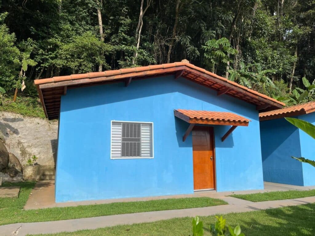 Frente do Chalé Canto da Viola, com uma janela e uma porta, atrás, árvores.