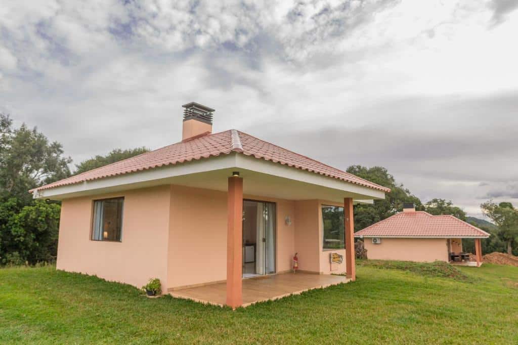Imagem da frente de um chalé do Hope Valley Adventure Resort durante o dia com gramado verde e do lado esquerdo o chalé.
