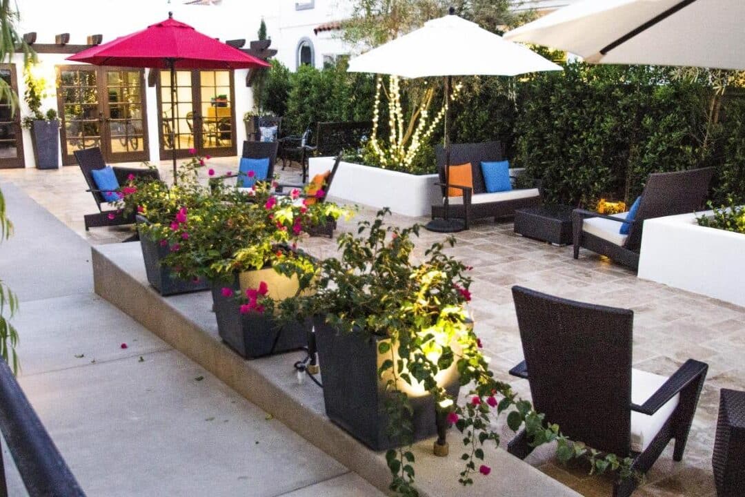 Área comum do Hotel Marisol. Ela é aberta e acomoda várias cadeiras e sofás, guarda-sóis e várias plantas.