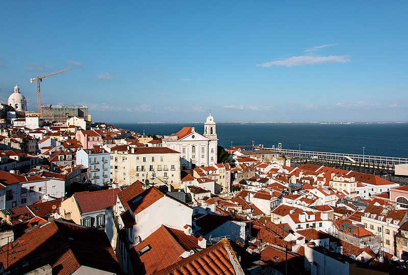 Imagem do miradouro de Santa Luzia com prédios a frente e o mar ao fundo. Representa o que fazer em Lisboa.