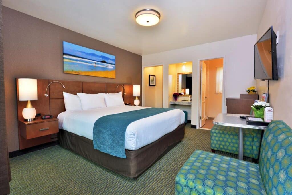 Quarto do Old Town Inn com uma cama de casal do lado esquerdo de frente para algumas poltronas e uma TV. Ao lado estão as portas para o banheiro.