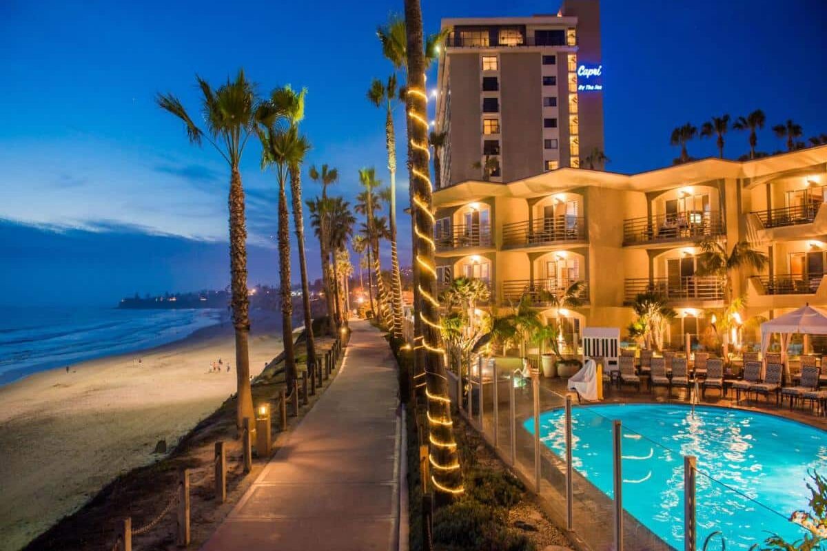 Piscina do Pacific Terrace Hotel. Ela e o hotel, todo iluminado, estão do lado direito. Do lado esquerdo estã a orla e a praia.