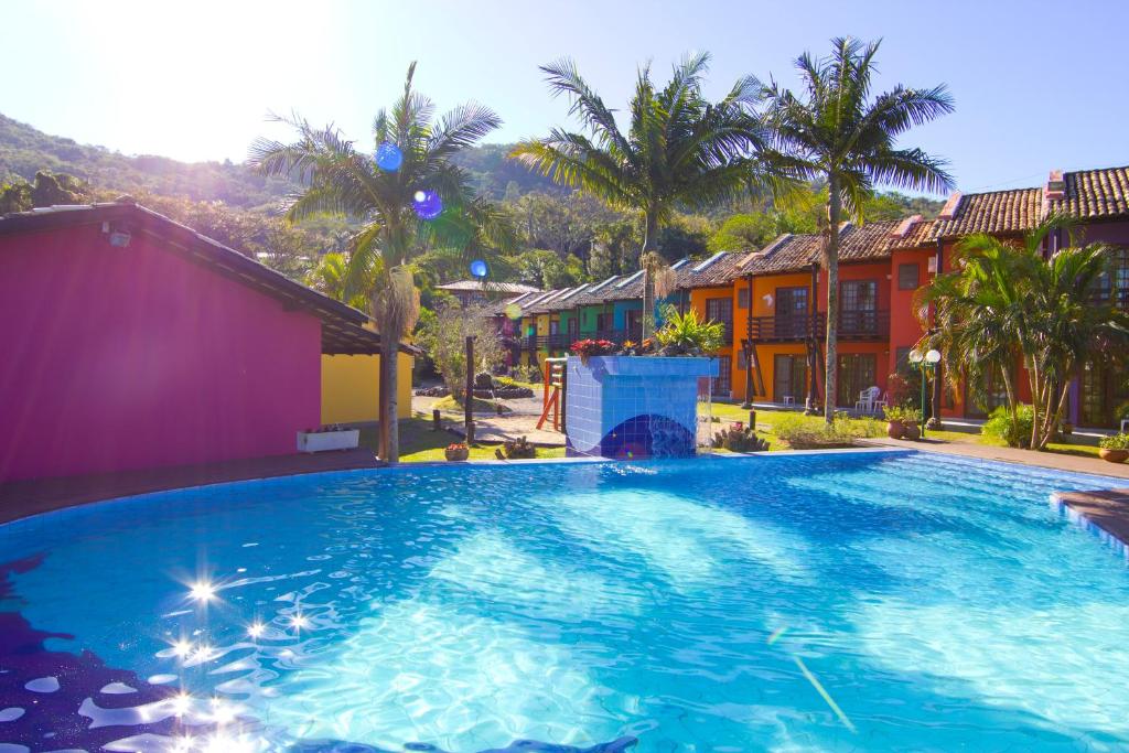 Piscina do Chalés Saint Germain durante o dia com a piscina a frente e ao fundo do lado direito vários chalés ao lado do outro.