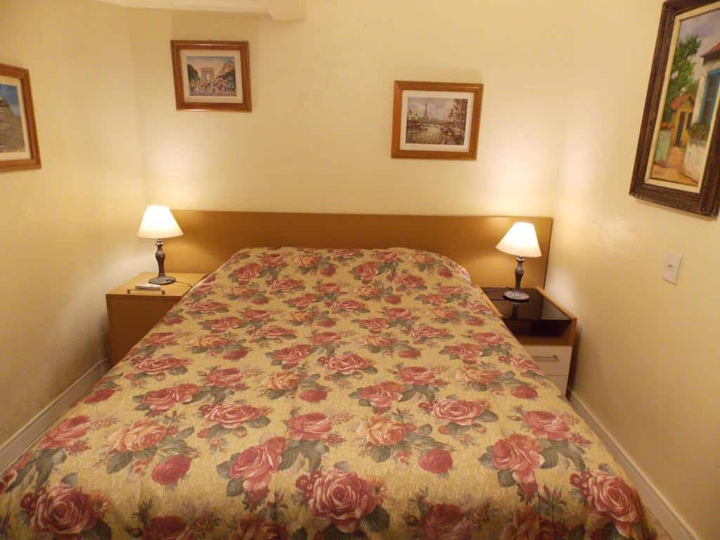 Quarto do Chalé no Centro de Canela com cama de casal, duas cômodas de madeira ao lado com luminária.