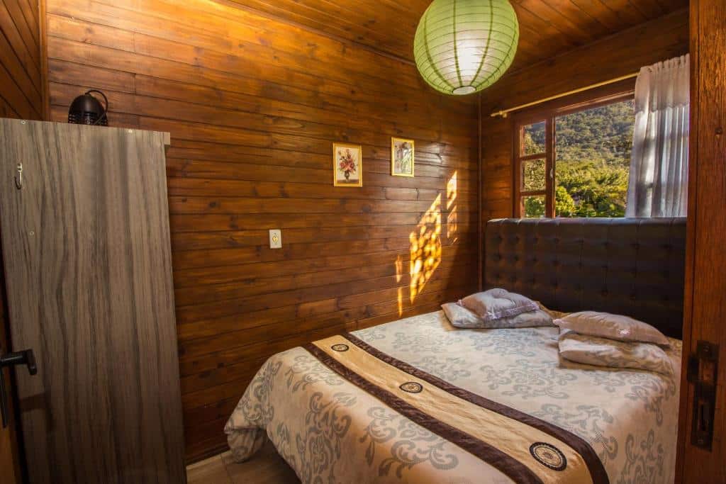 Quarto do Green Mountain Pousada com cama de casal do lado direito da imagem. Representa chalés em Florianópolis.
