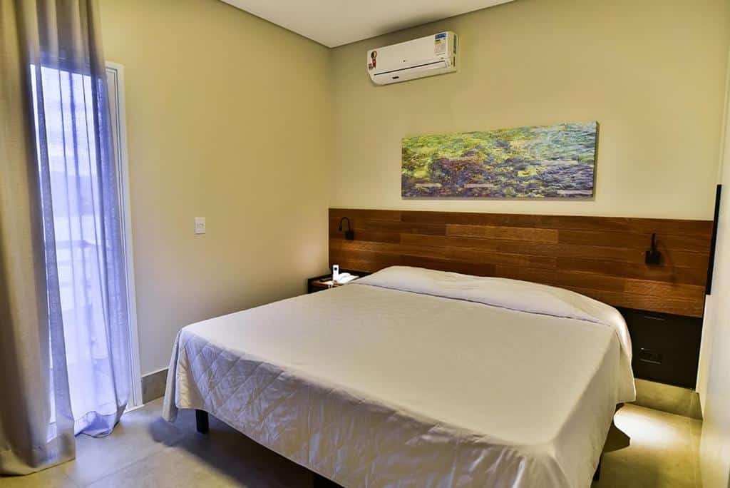 Quarto do Tayayá Aqua Resort com cama de casal no centro do quarto. Representa dos hotéis fazenda no Paraná.